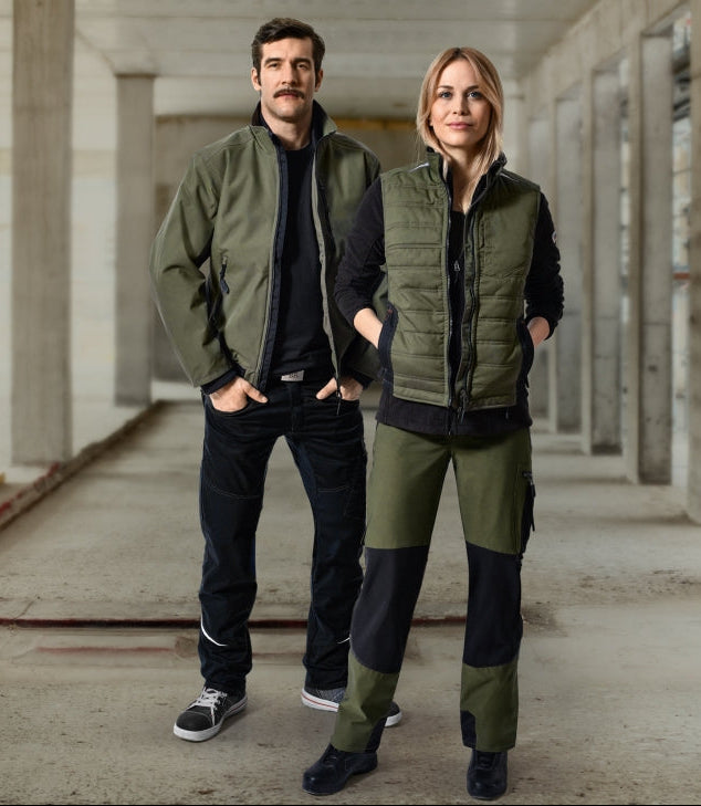 Handwerk & Industrie – Gruppe von Männern und Frauen in Arbeitskleidung mit roten Akzenten auf Baustelle