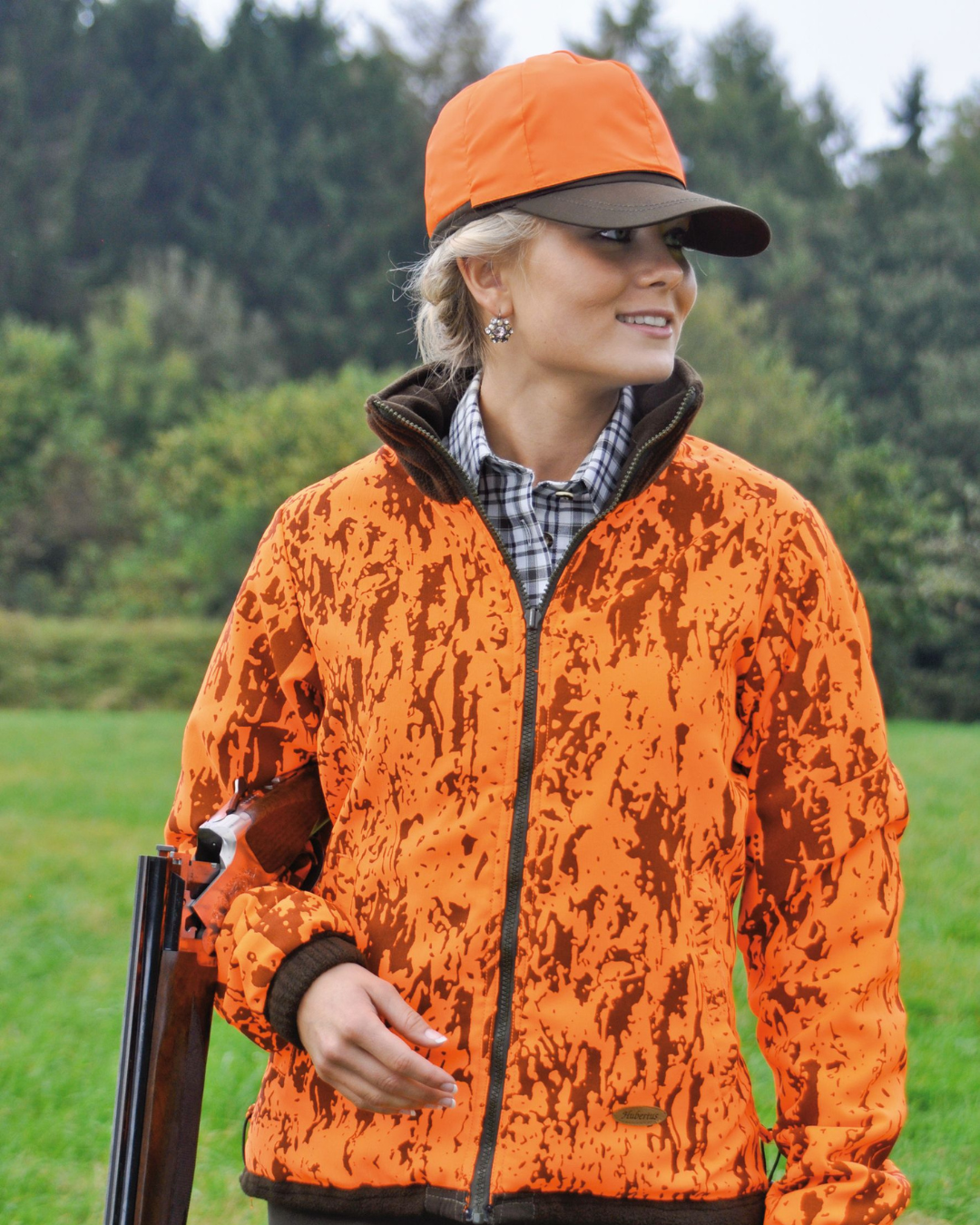 Jägerin in orangefarbener Signaljacke mit Gewehr – funktionale Damen-Jagdbekleidung für Sichtbarkeit und Sicherheit im Revier