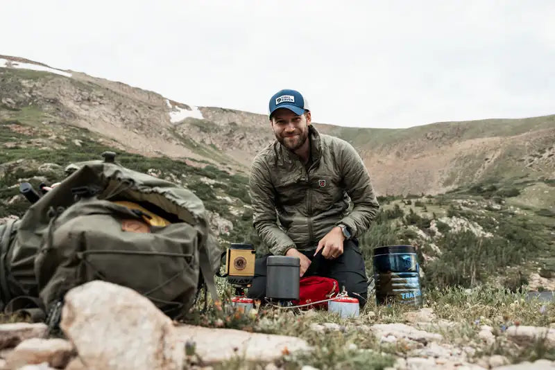 Outdoor-Rucksack mit Handschuhen und Flasche im Wald